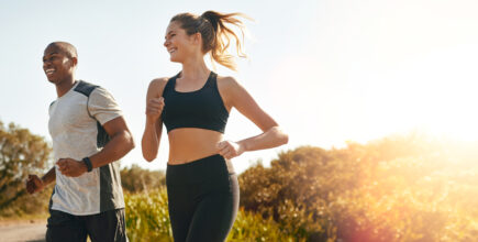 A man and a woman run side-by-side on a gravel trail