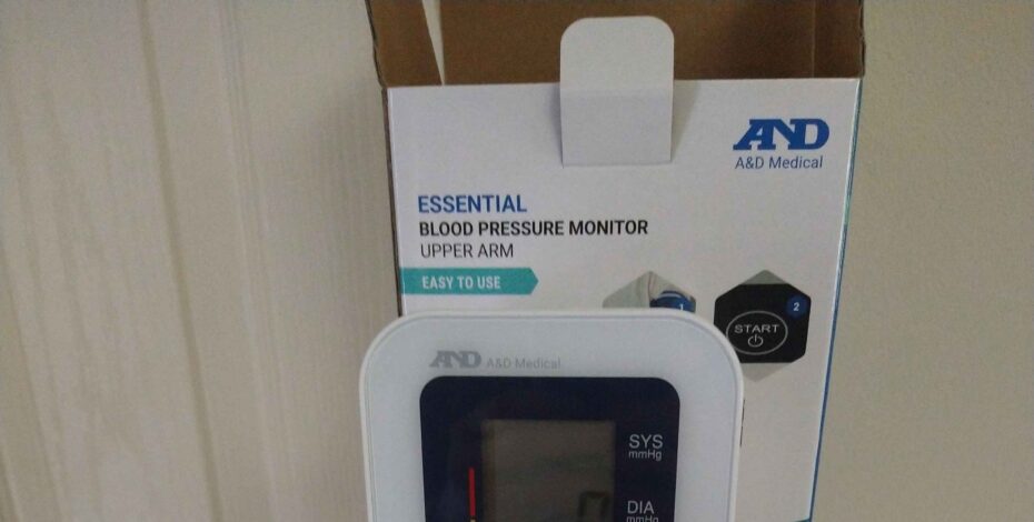 An opened blood pressure monitor box next to the actual monitor and cuff