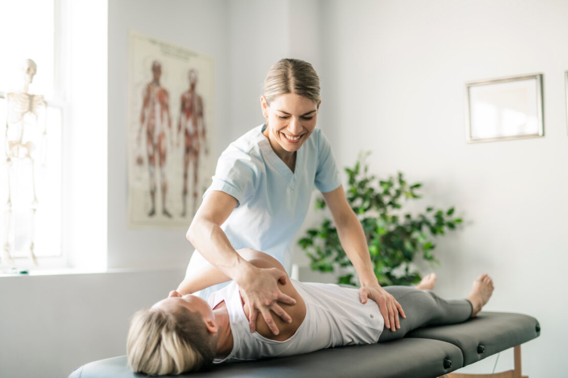 A chiropractor is adjusting a woman's arm and shoulder